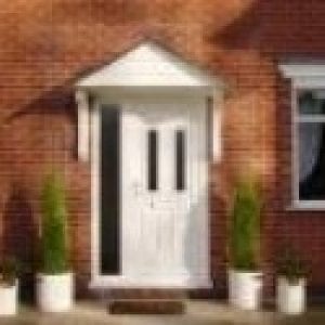 White door with a canopies above it finished in red brick similar to the walls of the house