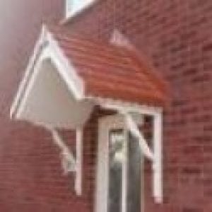 White door with a canopies above it finished in red brick similar to the walls of the house