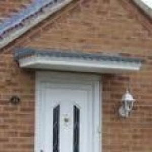 White door with a canopies above it finished in red brick similar to the walls of the house