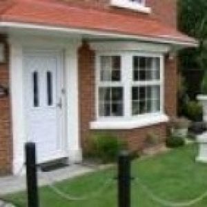 White door with a canopies above it finished in red brick similar to the walls of the house